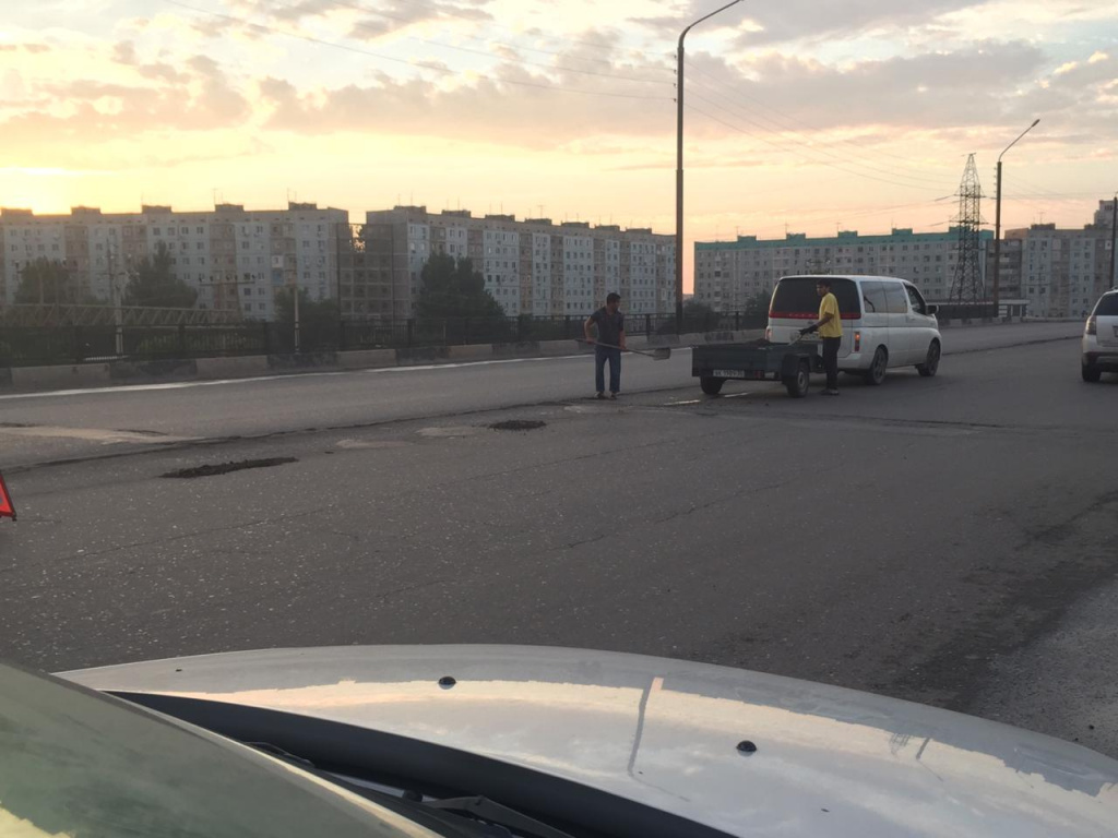 ремонт дорог в Астрахани, сотрудник минстроя ремонтирует дороги, астраханец чинит дороги
